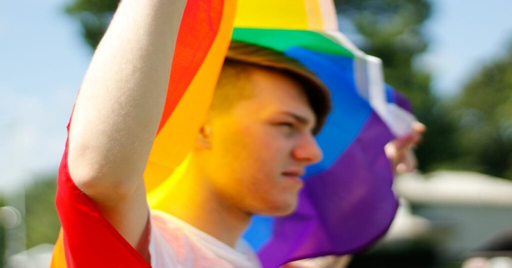 man holding rainbow flag