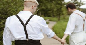 two guys wearing suspenders holding hands